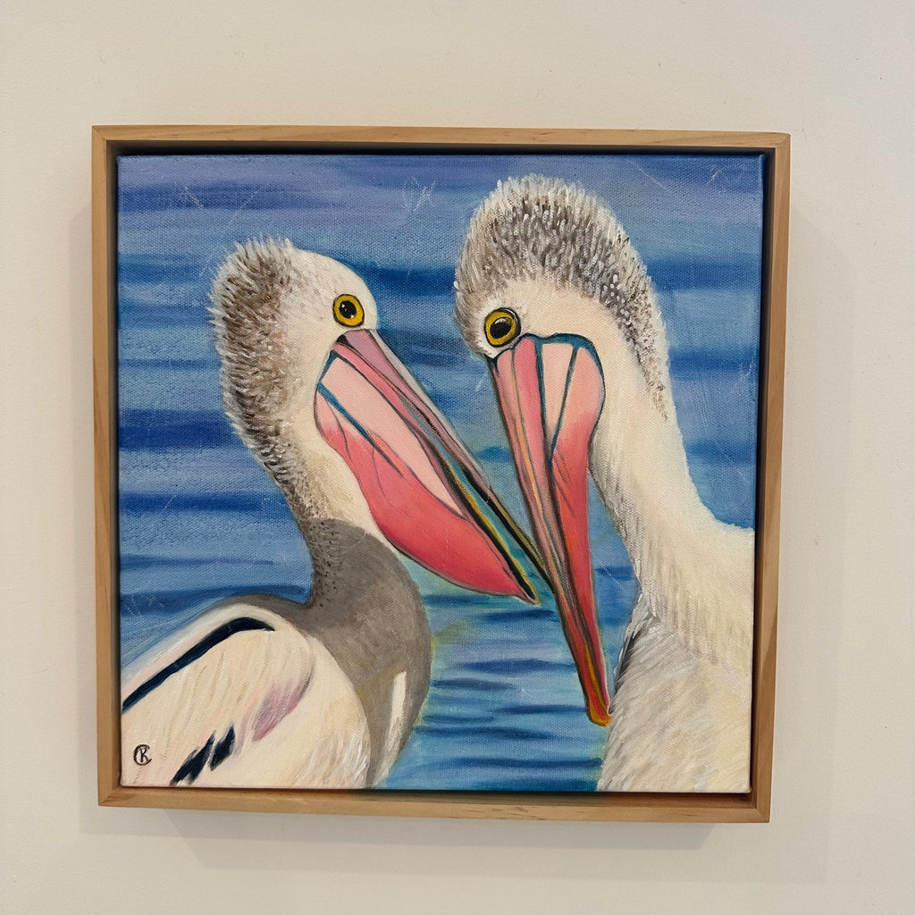 Pelican's in conversation facing each other with the clam water behind them the sun is shining bright. 