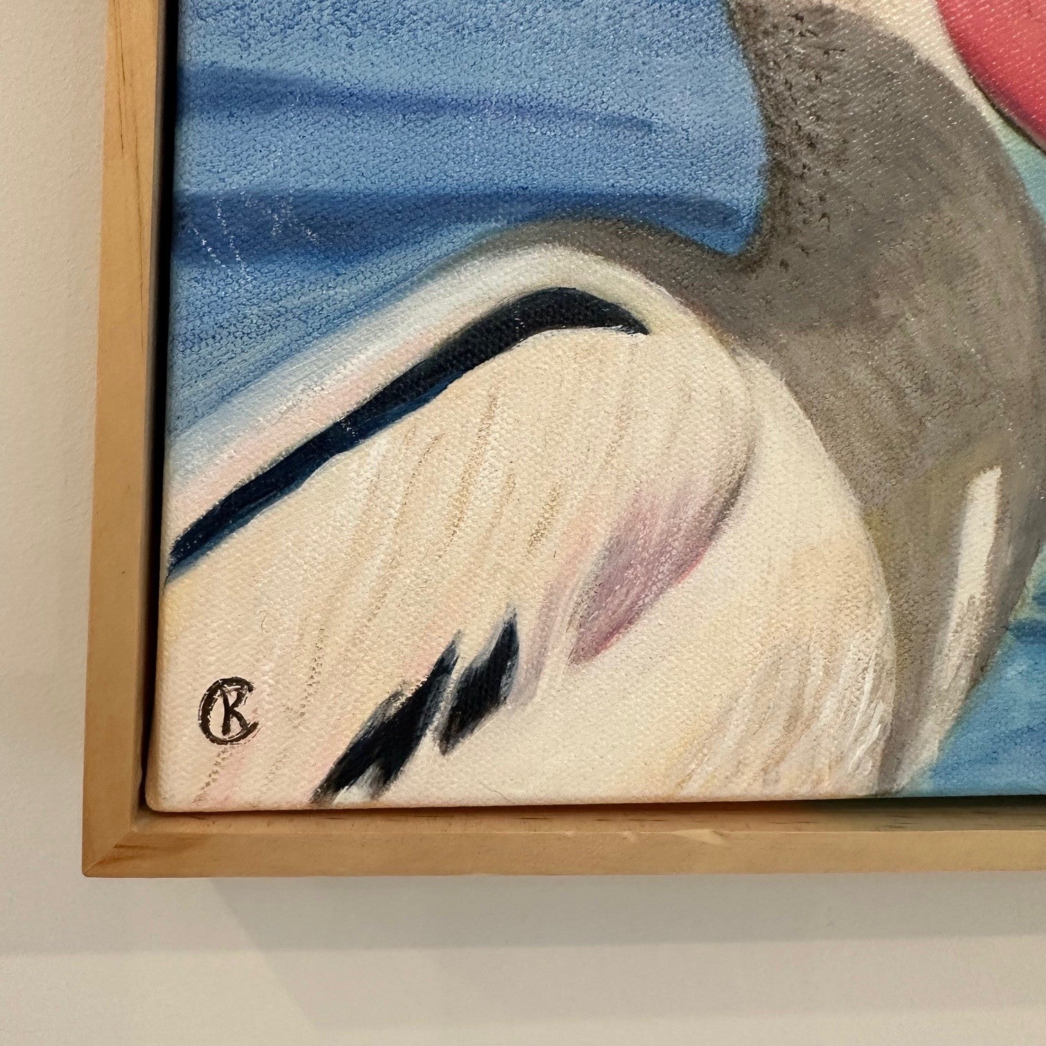 Framed closeup of the artist signature of a pelican painting with a  light background
